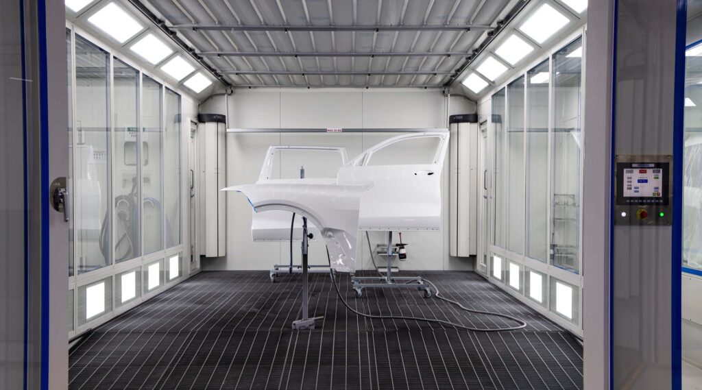 spray booth with finished car doors inside. clean minimalist with spray booth filters visible on the roof