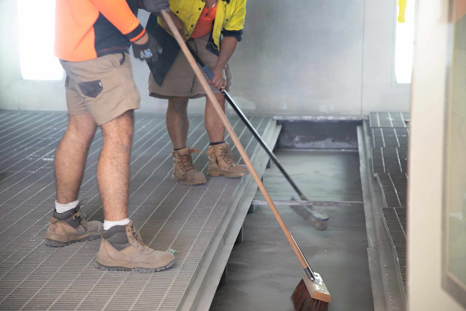 Technician cleaning a spray booth floor during maintenance